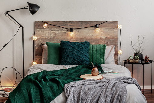 Emerald green and grey bedding on double bed with wooden headboard