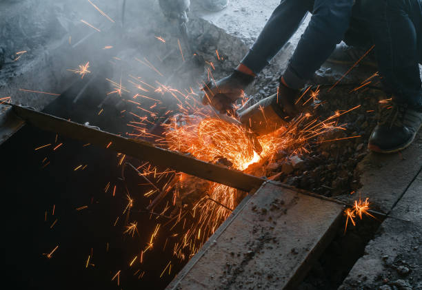 istock Male worker saws a disk grinding saw armature into a reinforced concrete panel, the destruction of the old house. Sparks from friction with metal. Rescue work. 1081013950