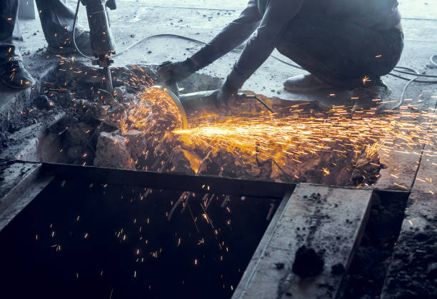 istock Male worker saws a disk grinding saw armature into a reinforced concrete panel, the destruction of the old house. Sparks from friction with metal. Rescue work. 1081013952