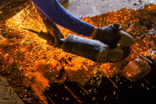 istock Male worker saws a disk grinding saw armature into a reinforced concrete panel, the destruction of the old house. Sparks from friction with metal. Rescue work. 1081013960