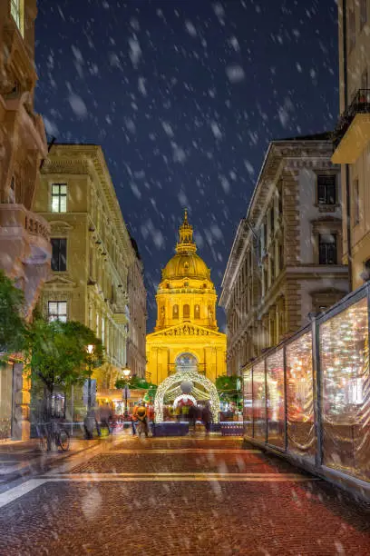 Photo of Budapest, Hungary - Snowy night at a Christmas market and shopping street with festive decoration and St.Stephen's basilica at background