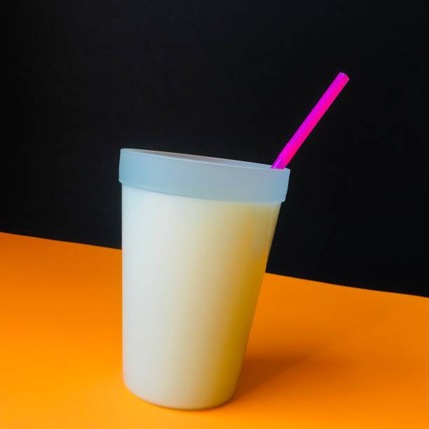 Cup of milk with straw on orange background.   iPhone