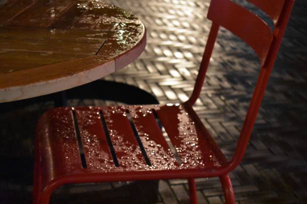Table and chair in the rain A red chair and a table outdoor in the rain by night rainy cafe stock pictures, royalty-free photos & images