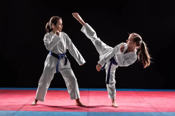 Two girls in taekwondo combat practicing martial arts. They wears kimonos
