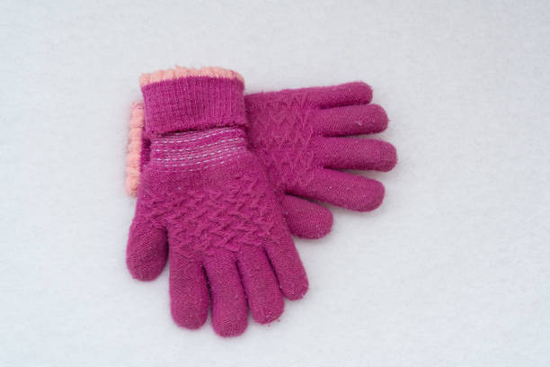 pink baby gloves on white snow background. winter clothes