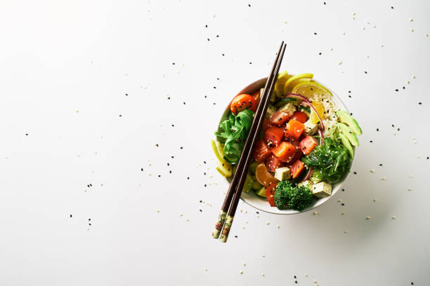 poke bowl with salmon, avocado, cucumber, arugula, broccoli, rice, carrot and sweet onions with chuka salad, chopsticks isolated over white background. top view poke bowl with salmon islated on white background. top view marinated photos stock pictures, royalty-free photos & images