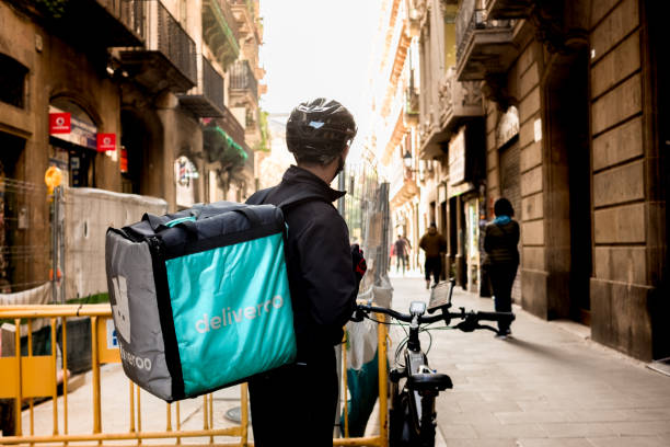 young Deliveroo delivey service company by bike in the streets of city working during the day stock photo