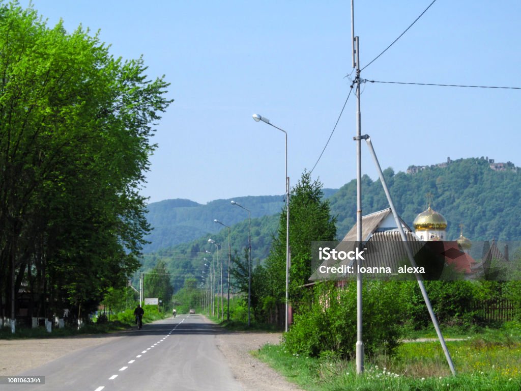 Summer landscape of Ivan Chendey street in Khust with the ruins of an ancient fortress on a hill Summer landscape of Ivan Chendey street in Khust with the ruins of an ancient fortress on a hill. Beautiful mountain rural landscape in Transcarpathia, Ukraine Ancient Stock Photo