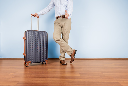 Man showing thumbs up beside suitcase