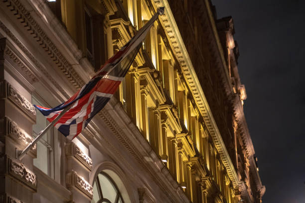 Close up image of an illuminated neon sign spelling out the words 'London Calling' in reference to the song by The Clash of the same name. Behind the neon words is the British flag - the Union Jack - in its famous red, white and blue. Horizontal colour image with copy space.