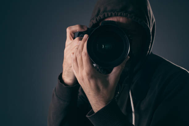 Hooded photographer behind DSLR camera