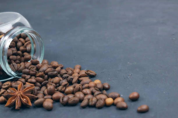 istock roasted coffee beans poured from a glass jar. angular placement of the coffee object. on dark concrete. horizontal view. copy space 1081073342