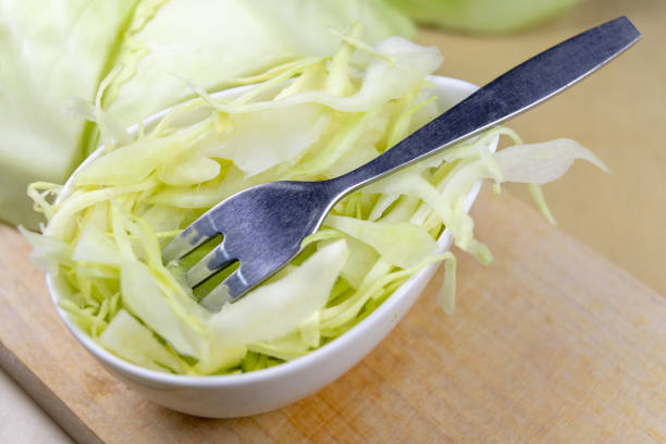 Fresh white cabbage cut into strips on the kitchen table. Vegetables prepared for salad. Light background.