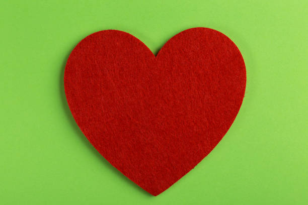 istock Red felt heart on bright green background 1081113990