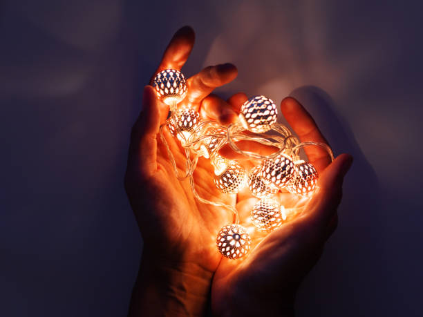 istock Hands with light bulbs. Metal light bulbs with delicate pattern shine in dark. Holiday decoration with magic light reflections. 1081122876