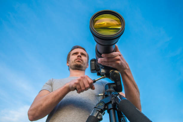 istock The man work with the camera on a tripod against the blue sky background 1081136366