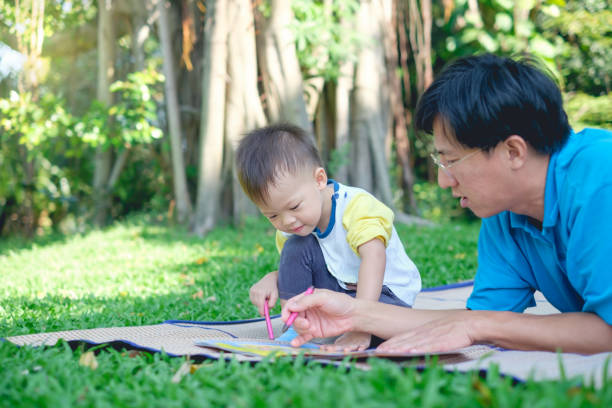 cute little asian 2 - 3  years old toddler boy child painting with crayons, kid coloring with father at park - 2 3 years fotos imagens e fotografias de stock