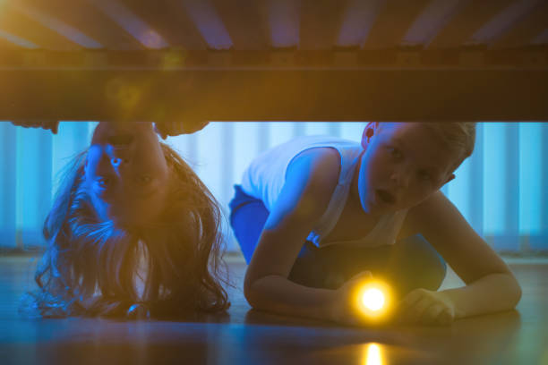 istock The boy and girl with a flashlight look under bed. night time 1081139492