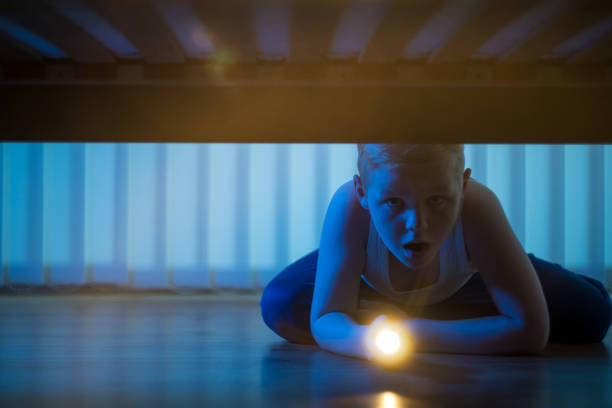 istock The frightened boy with a flashlight look under bed. night time 1081139568