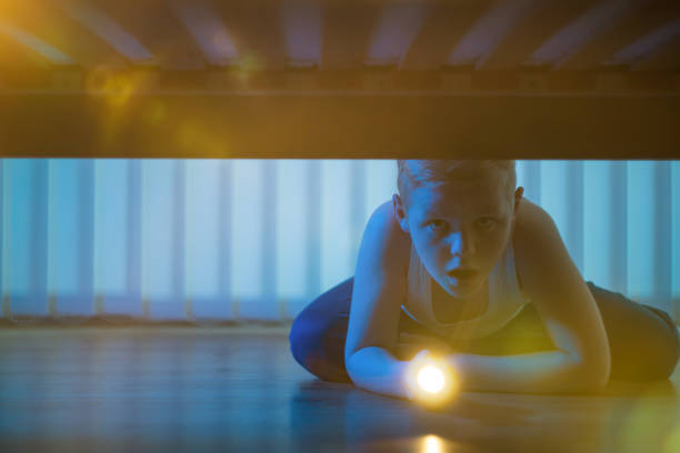 istock The frightened boy with a flashlight look under bed. night time 1081139574