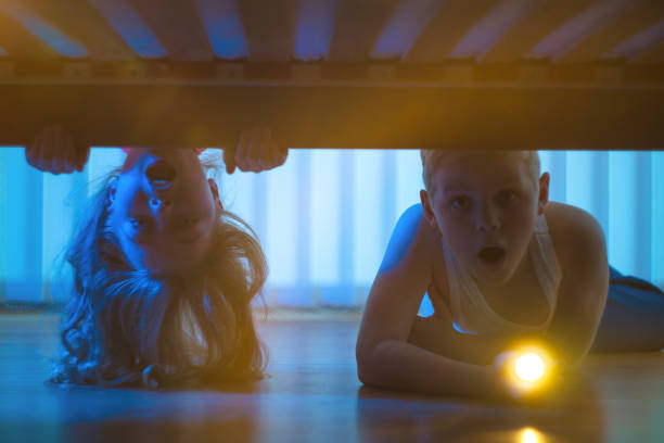 istock The surprised boy and girl with a flashlight look under bed. night time 1081139638