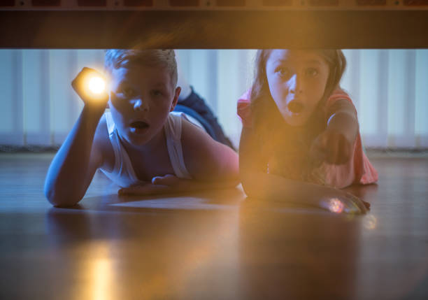 istock The scared boy and girl lay on the floor with a flashlight. night time 1081139700