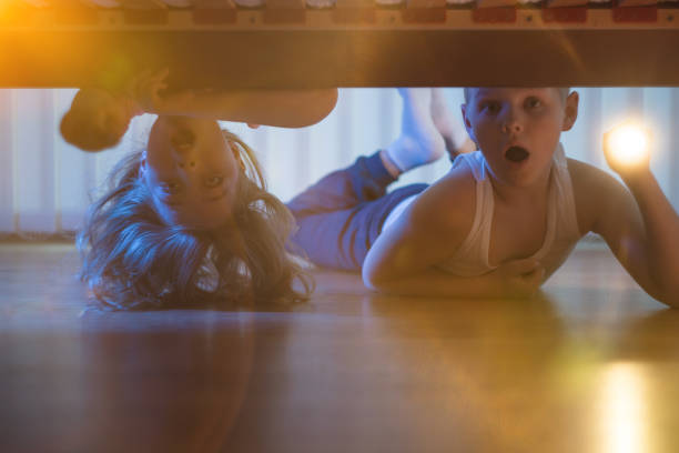 istock The scared boy and girl with a flashlight look under bed. night time 1081139764