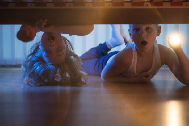 istock The scared boy and girl with a flashlight look under bed. night time 1081139848
