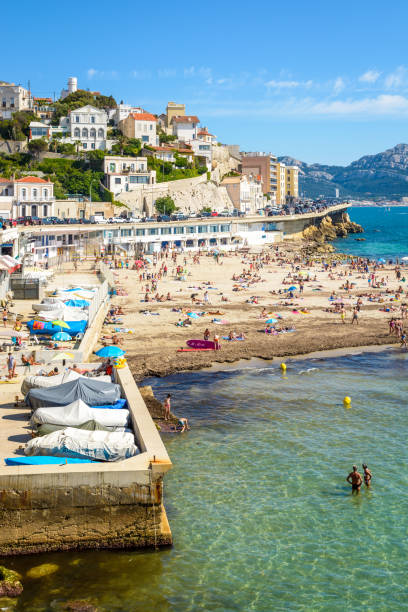 People sunbathing and swimming on the Prophet beach in Marseille, France. Marseille, France - May 19, 2018: People sunbathing and swimming on the Prophet beach, a very popular family beach located on the Kennedy corniche, on a hot and sunny spring day. oracle building stock pictures, royalty-free photos & images