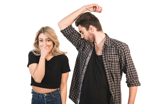 The man smells armpits near the woman on the white background