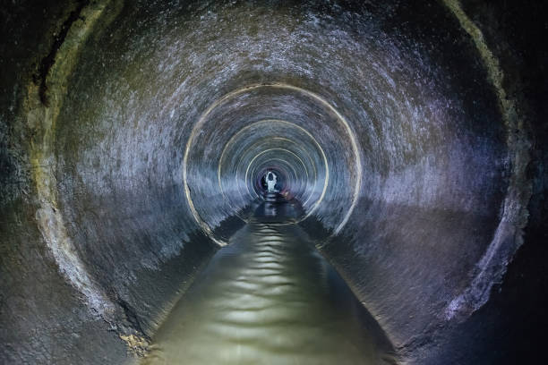 istock Diggers (urban explorers) are exploring underground river flowing in round sewer tunnel 1081158058