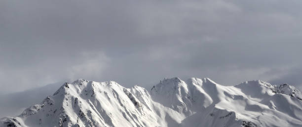 istock Panoramic view on evening snowy sunlight mountains and gray sky 1081176674