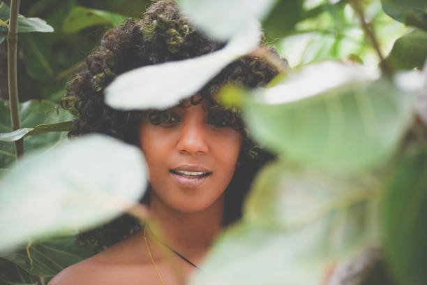 Beautiful african american woman with big natural hair in a nature area, posed model shoot, editorial fashion. She wears a retro outfit and looks like she could be from any decade, specifically the 70's. She is confident, fierce and has a strong presence. Outdoors in a film style shoot