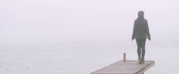 istock Woman in black standing on dock in winter 1081181742