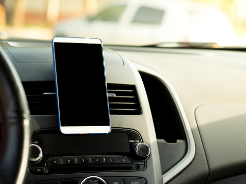 teléfono móvil situado en el centro de la consola del vehículo. Teléfono de la pantalla en negro en el coche photo