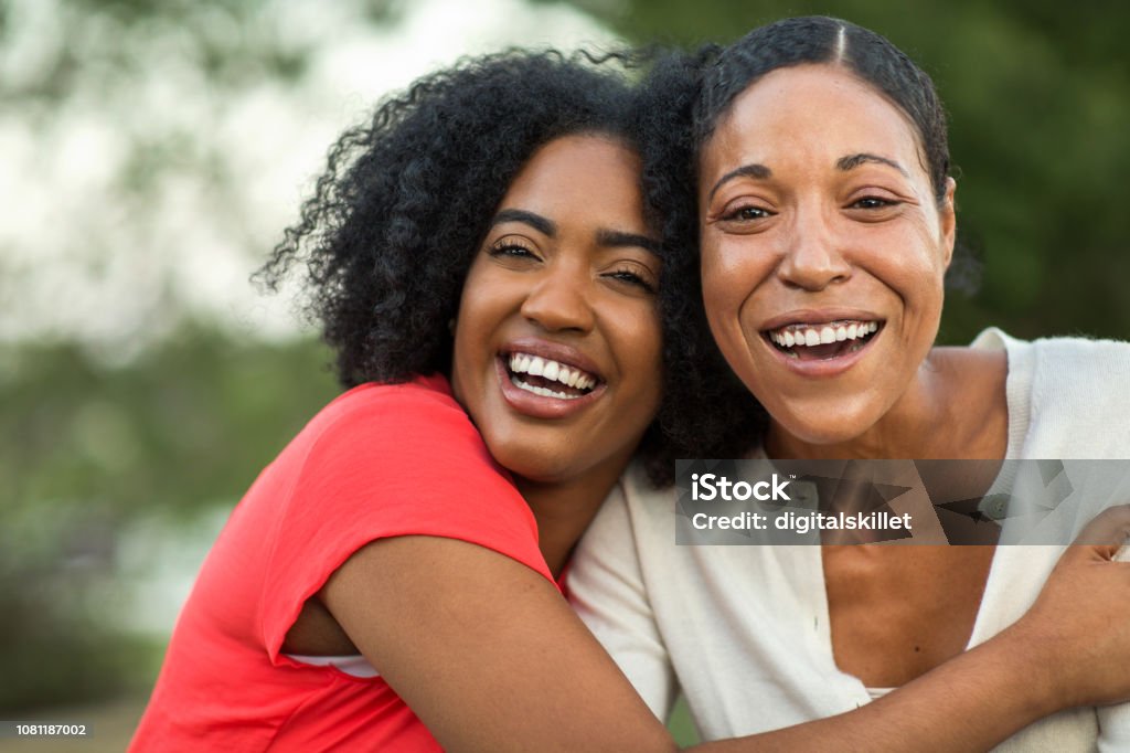 African American mother hugging her adult daughter. Mother and her daughter hugging sitting outside. Mother Stock Photo