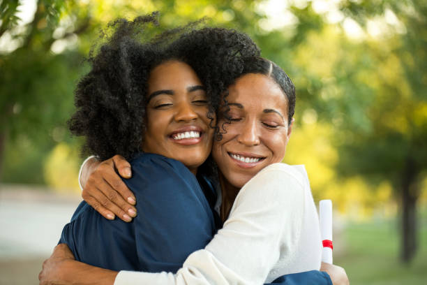 Mother and her daughter hugging at her graduation African American mother hugging her daughter at her graduation. college student and parent stock pictures, royalty-free photos & images