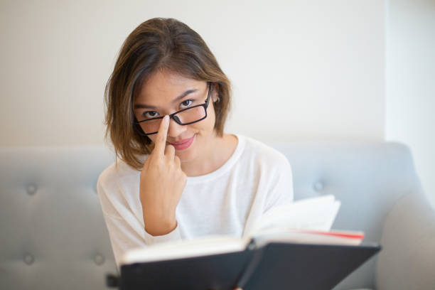 istock Serious young woman reading book on sofa at home 1081190926