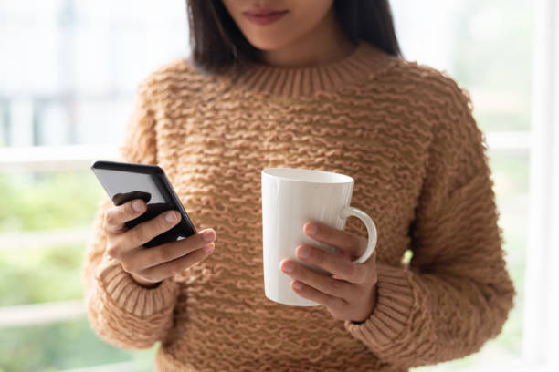istock Close-up of serious lady using smartphone and drinking coffee 1081198588