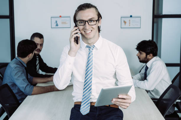 gerenciador de jovem sorridente usando telefone e tablet - smart phone digital tablet group of people manager - fotografias e filmes do acervo