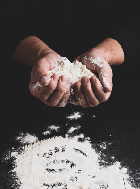 istock white wheat flour in male hands, black background 1081208968