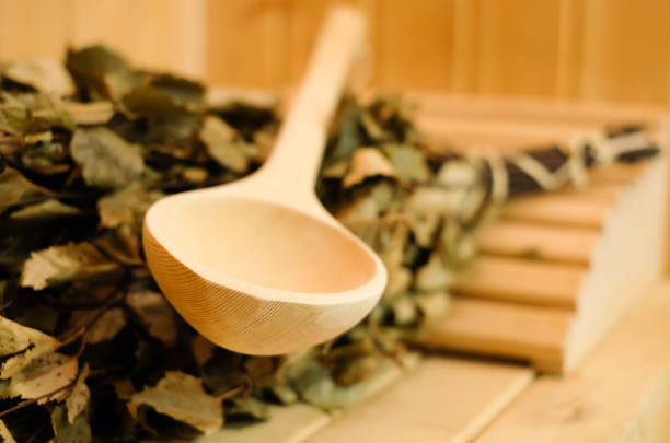 Sauna accessories close up in traditional finnish or russian sauna, birch broom and wooden scoop. Rest and relaxation in the spa to keep warm in the cold winter stock photo