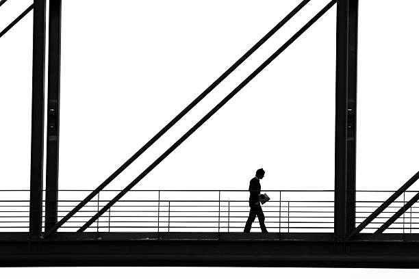 Silhouette of Man Walking Down Walkway stock photo