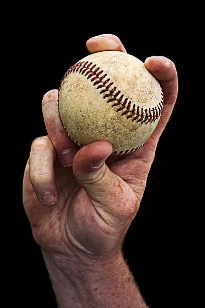 Photo of Man's Hand Holding Baseball Against Black Background
