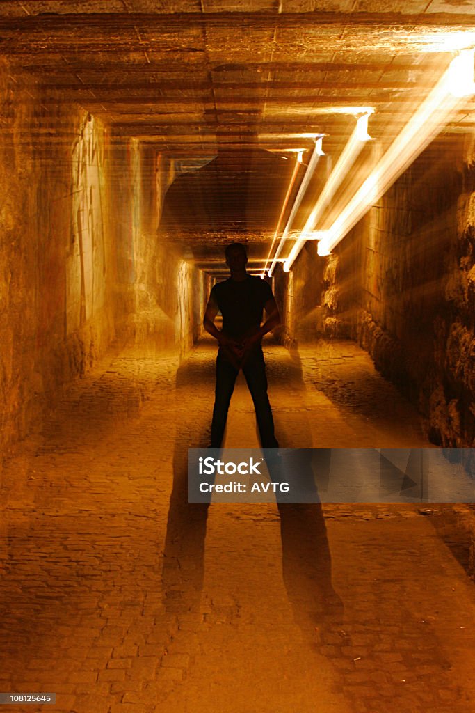 Hombre de pie en un túnel de ladrillo con sombra - Foto de stock de Correr libre de derechos