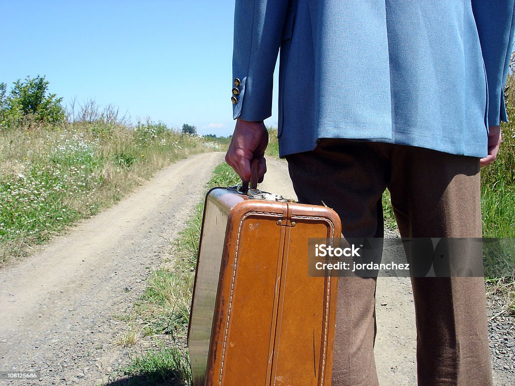 Hombre que agarra maletín on Rural Road - Foto de stock de Huido libre de derechos