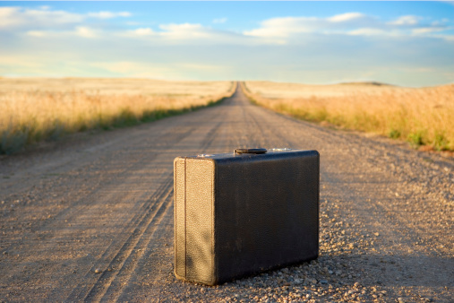 Image of a suitcase sitting on a dirt road.