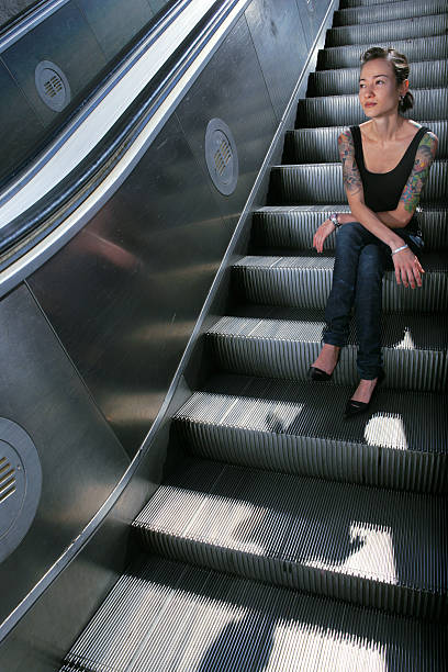 jeune femme assise sur l'escalator escalier - tattoo japanese culture women asian ethnicity photos et images de collection