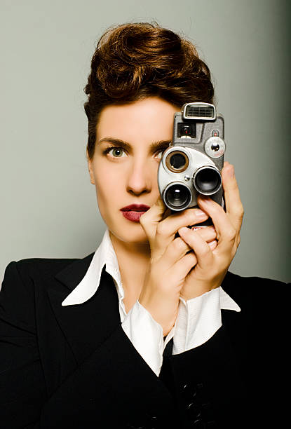 Waist-up of a male photographer looking through the viewfinder of his DSLR camera taking photo of itself front of mirror in the room.