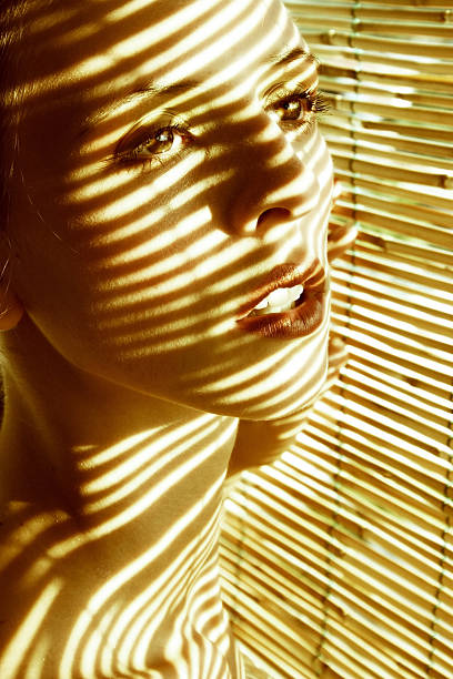 istock Young Woman Standing Near Blinds with Shadows on Face 108126165